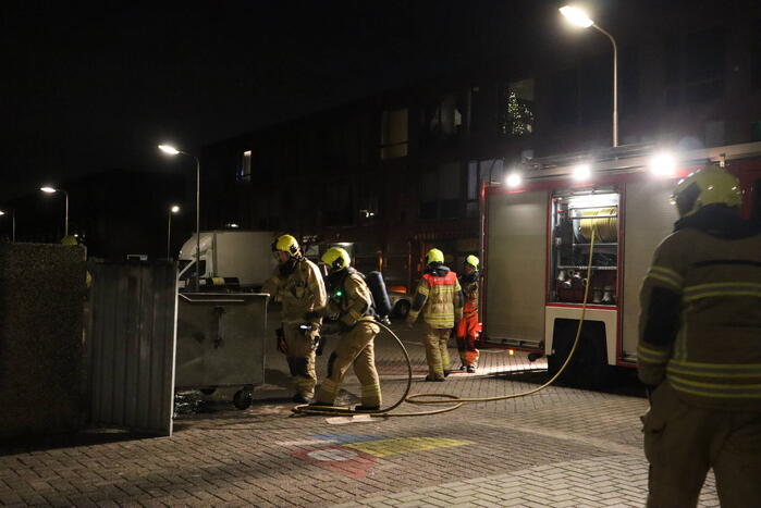 Brandweer blust brandende papiercontainer