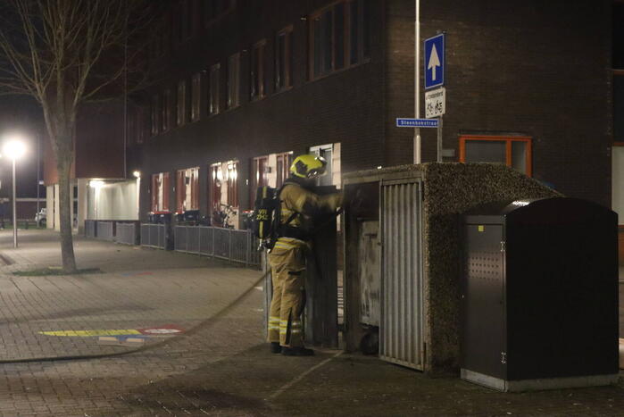 Brandweer blust brandende papiercontainer