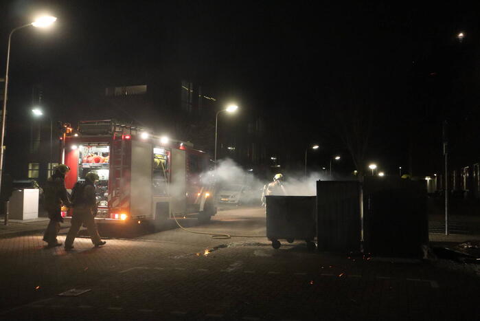 Brandweer blust brandende papiercontainer