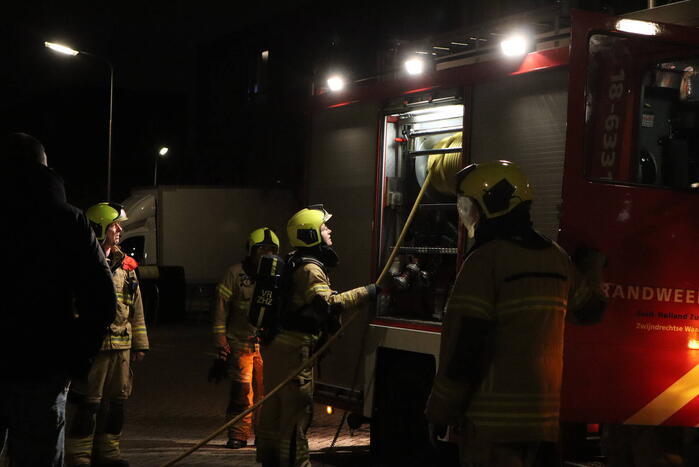 Brandweer blust brandende papiercontainer