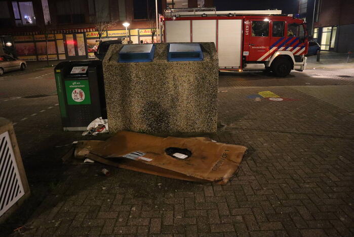 Brandweer blust brandende papiercontainer