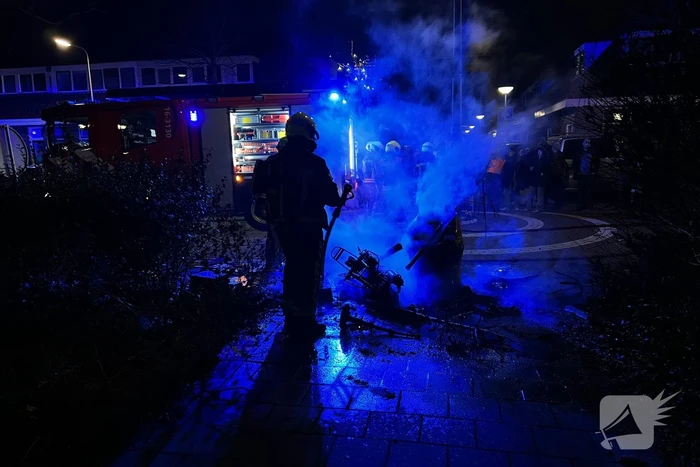 Brandweer blust brandende vuurton en scooter