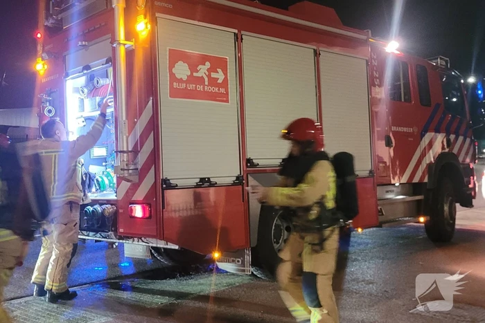 Brandweer blust brandend heg naast pand