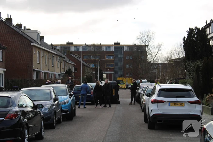 Auto op op zijn zijkant na botsing in woonwijk