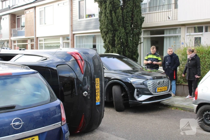 Auto op op zijn zijkant na botsing in woonwijk