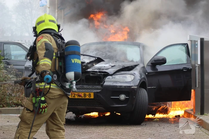 Auto vliegt in brand voor ingang carwash