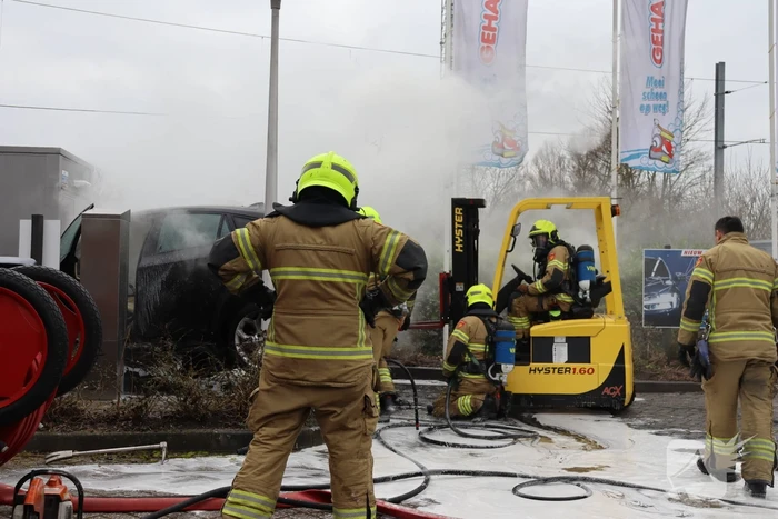 Auto vliegt in brand voor ingang carwash