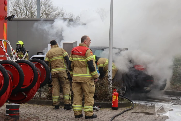 Auto vliegt in brand voor ingang carwash