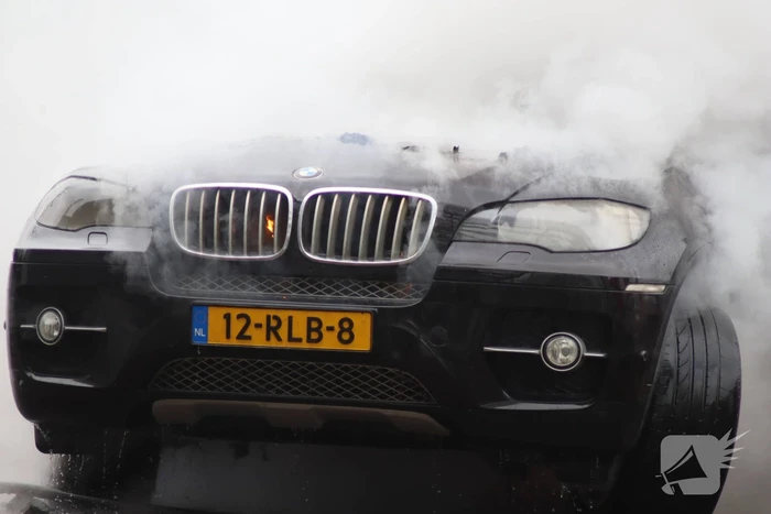 Auto vliegt in brand voor ingang carwash