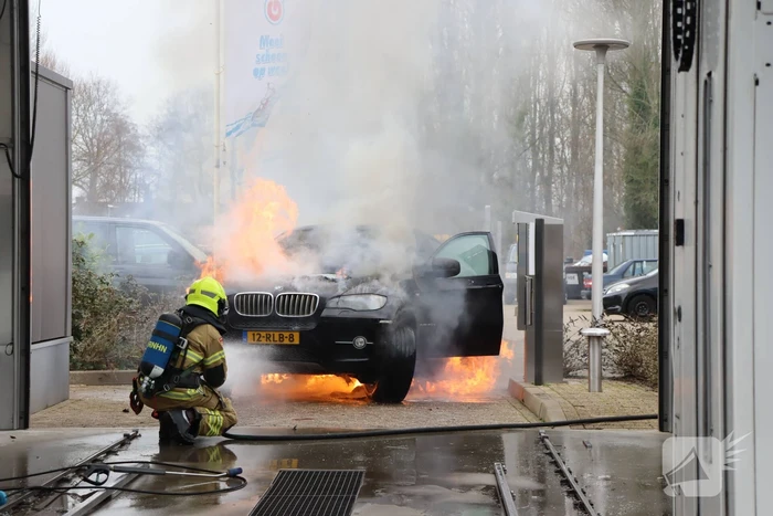 Auto vliegt in brand voor ingang carwash