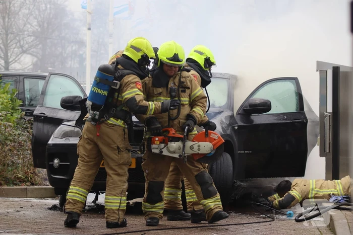 Auto vliegt in brand voor ingang carwash
