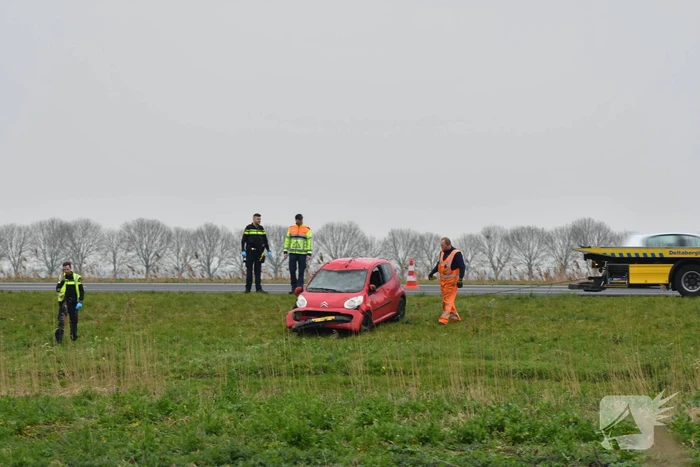 Auto belandt op zijn kop naast snelweg