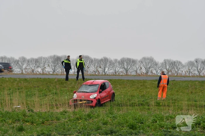 Auto belandt op zijn kop naast snelweg