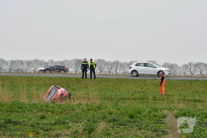 Auto belandt op zijn kop naast snelweg
