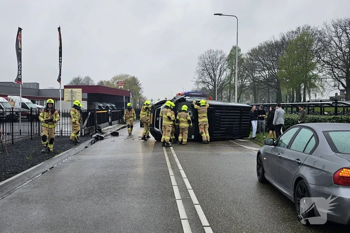 Bestelbus botst op hek en belandt op zijkant
