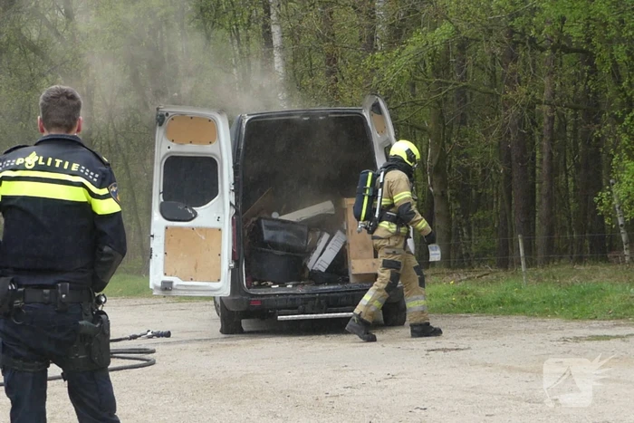 Bestelbus met afval in brand gestoken op parkeerplaats bij bos, twee aanhoudingen