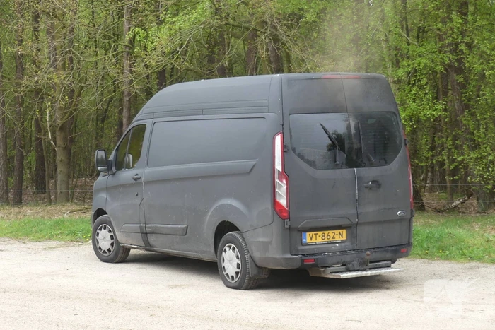 Bestelbus met afval in brand gestoken op parkeerplaats bij bos, twee aanhoudingen