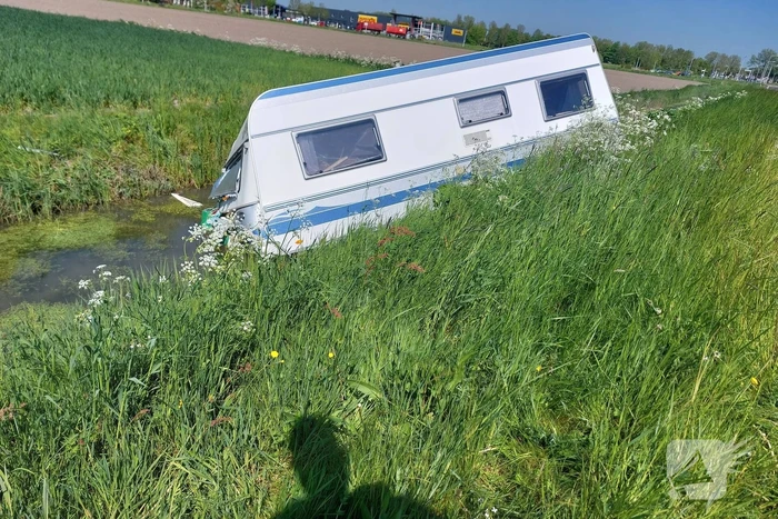Caravan raakt los van auto en belandt in sloot