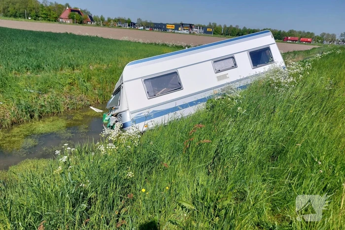 Caravan raakt los van auto en belandt in sloot