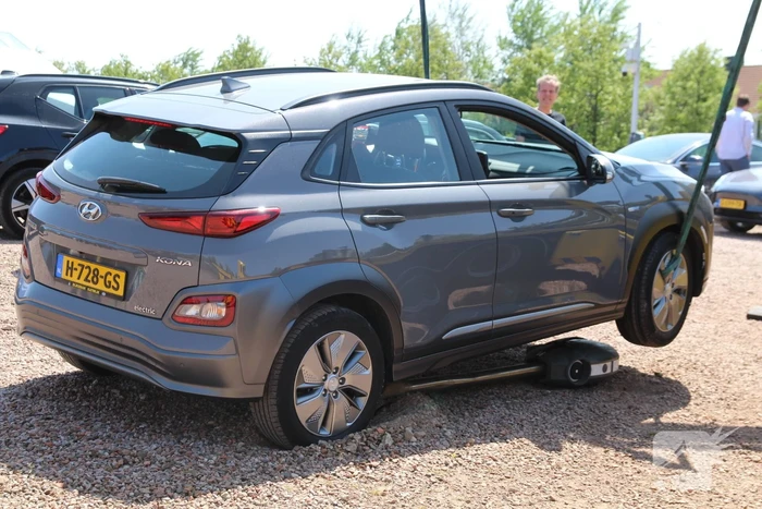Elektrische personenauto rijdt oplaadpaal uit de grond