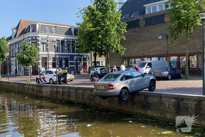 Auto blijft op randje van kade hangen boven gracht