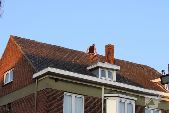 Man klimt op woning en gooit dakpannen naar hulpdiensten