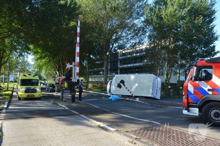 Vrachtwagen kantelt in bocht op overweg