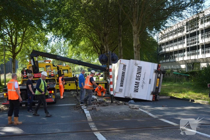 Vrachtwagen kantelt in bocht op overweg
