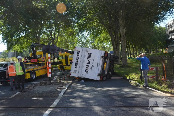 Vrachtwagen kantelt in bocht op overweg