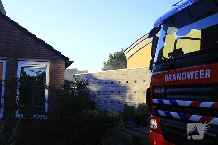 Brandweer blust brandende prullenbak in schuur