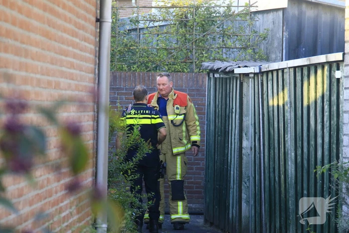 Brandweer blust brandende prullenbak in schuur