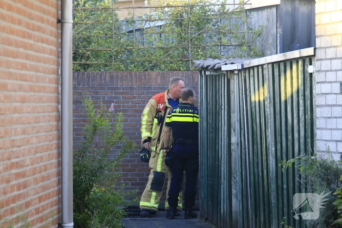 Brandweer blust brandende prullenbak in schuur