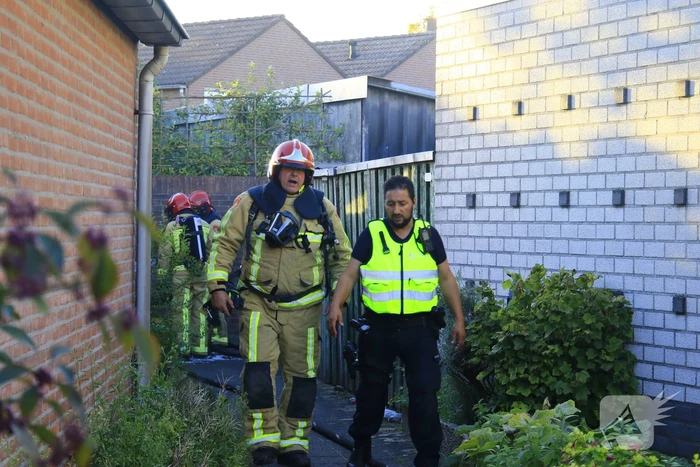Brandweer blust brandende prullenbak in schuur