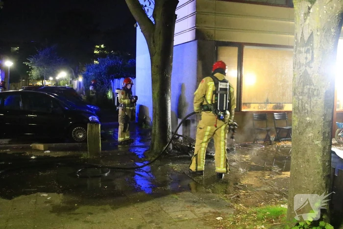 Scooter in brand tegen woning