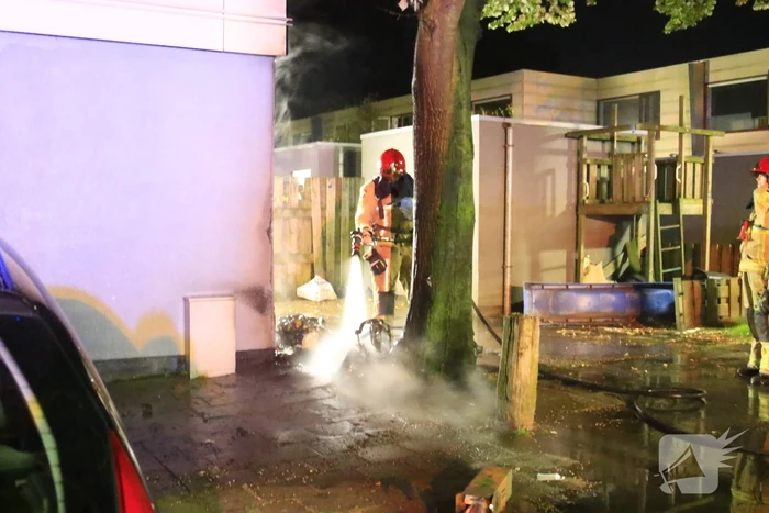 Scooter in brand tegen woning
