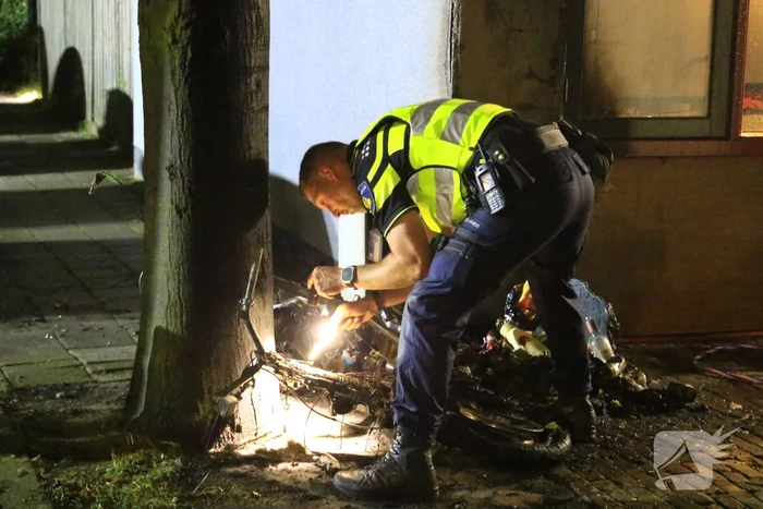 Scooter in brand tegen woning