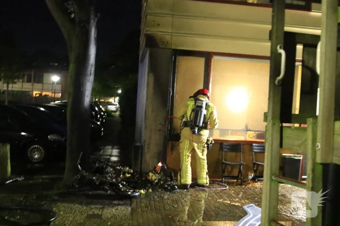 Scooter in brand tegen woning