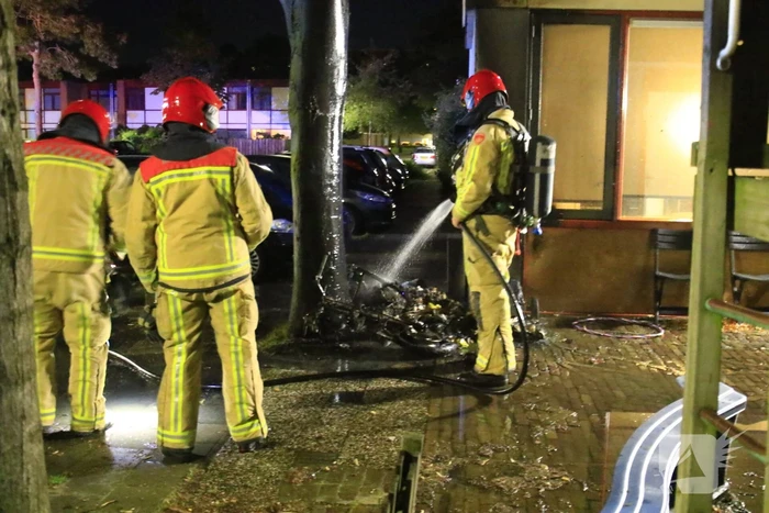 Scooter in brand tegen woning