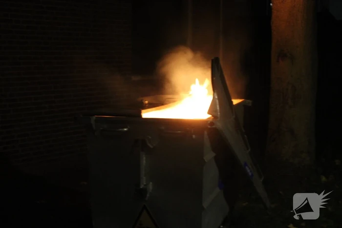 Vlammen slaan uit afvalcontainer