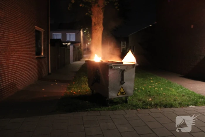 Vlammen slaan uit afvalcontainer
