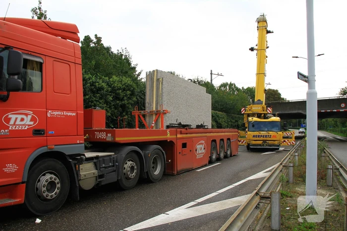 Vrachtwagen geladen met betonplaten vast onder spoorbrug