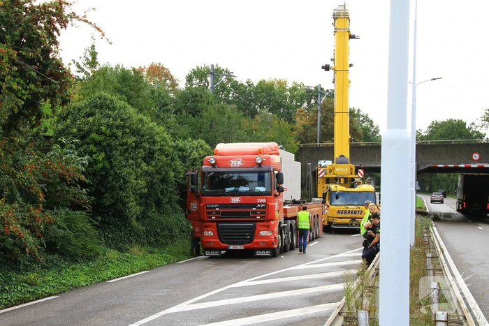 Vrachtwagen geladen met betonplaten vast onder spoorbrug