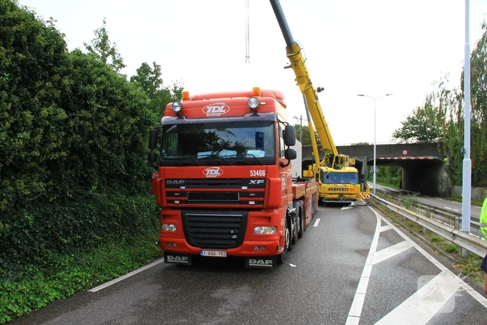 Vrachtwagen geladen met betonplaten vast onder spoorbrug