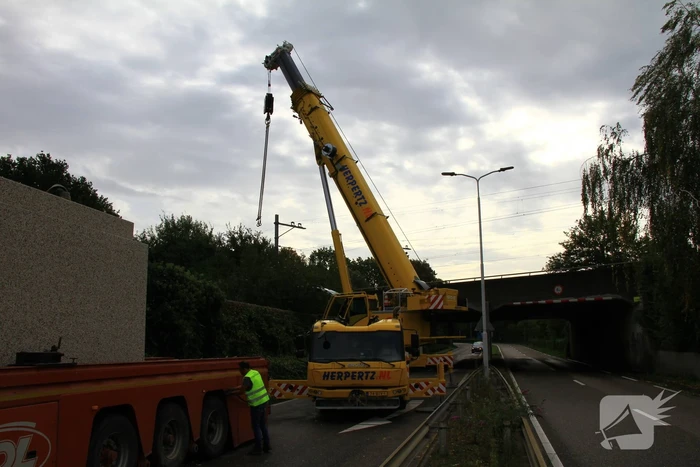 Vrachtwagen geladen met betonplaten vast onder spoorbrug