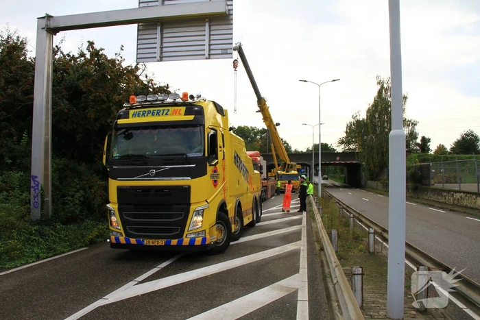 Vrachtwagen geladen met betonplaten vast onder spoorbrug