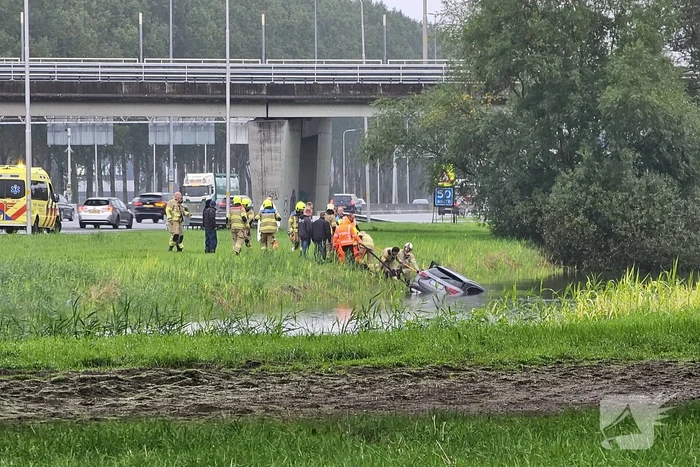 Auto raakt te water naast snelweg