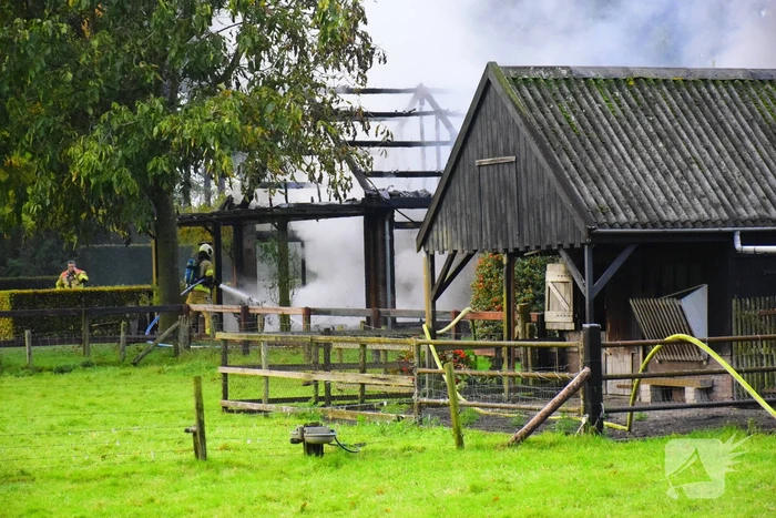Grote brand in loods dreigt over te slaan naar woning