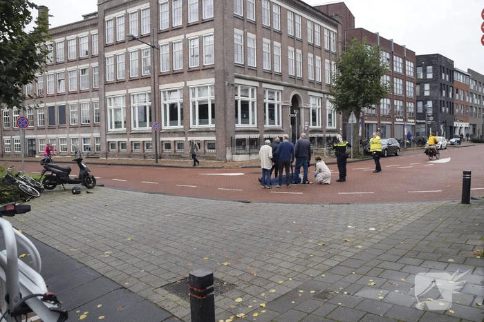 Persoon op scooter onderuit op kruising