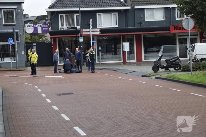 Persoon op scooter onderuit op kruising
