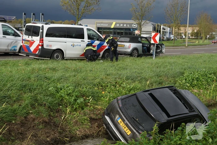 Omstanders halen inzittenden uit te water geraakt voertuig